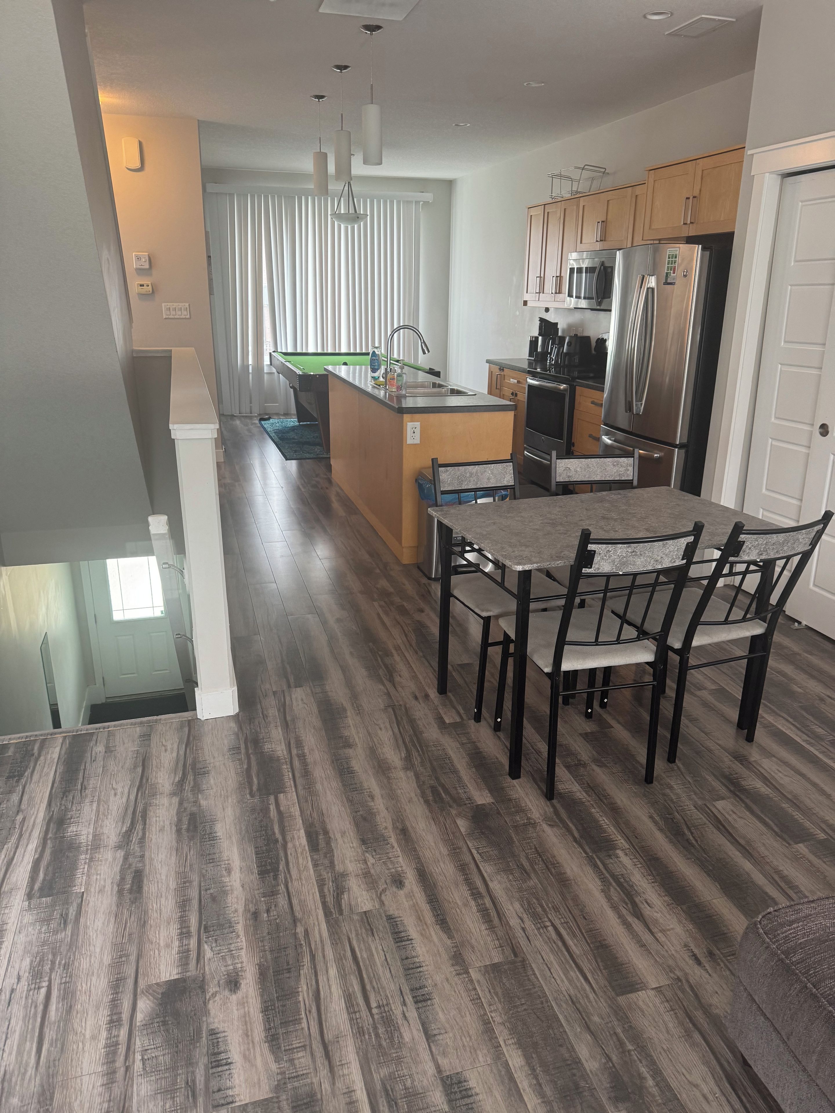 A modern kitchen with a central island, stainless steel appliances, and a dining area with a table and chairs.