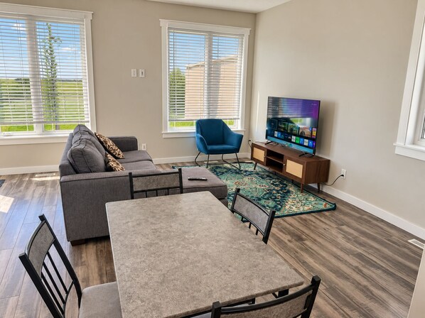 A living room with a sofa, a blue chair, a TV, and a dining table.