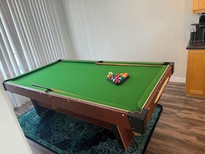 Ein Billardtisch mit Spielbällen und einem Queue.