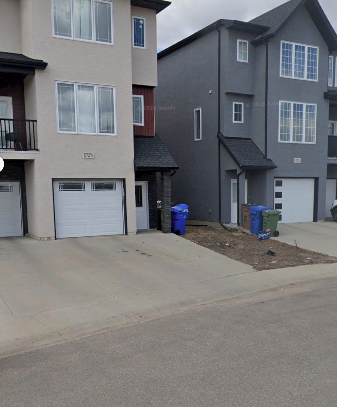 A residential building with a garage, a small porch, and a driveway.