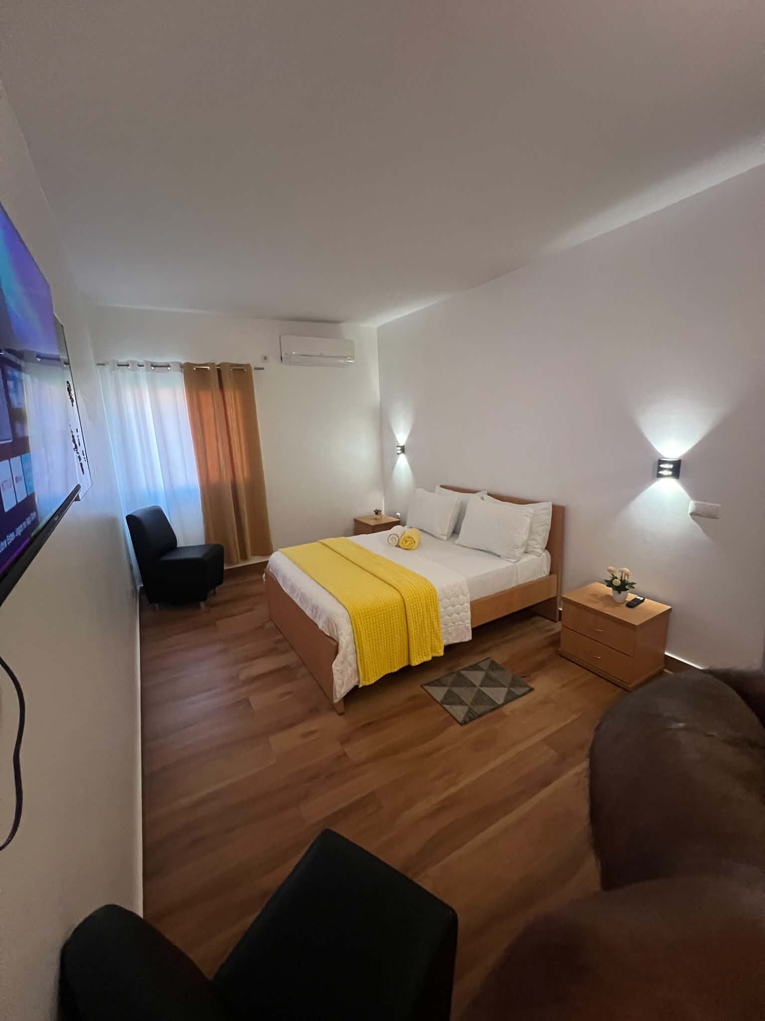Una habitación de hotel con cama, mesitas de noche, escritorio, silla y televisor.