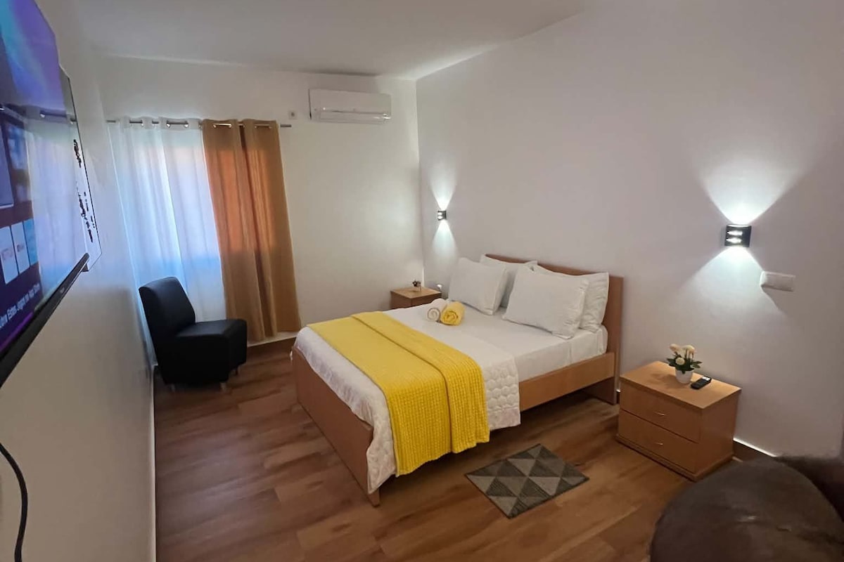 Una habitación de hotel con cama, mesitas de noche, escritorio, silla y televisor.