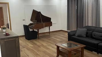 Un salon moderne avec un piano à queue, une table basse en verre et un canapé de couleur foncée.