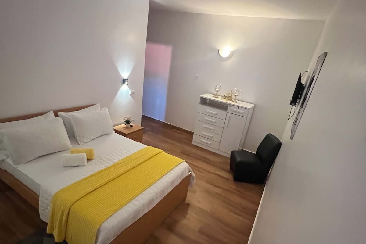 Un dormitorio con cama, mesita de noche, lámpara y un escritorio con cajones.