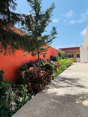 Un sendero que conduce a un edificio con pared exterior roja y cielo despejado.