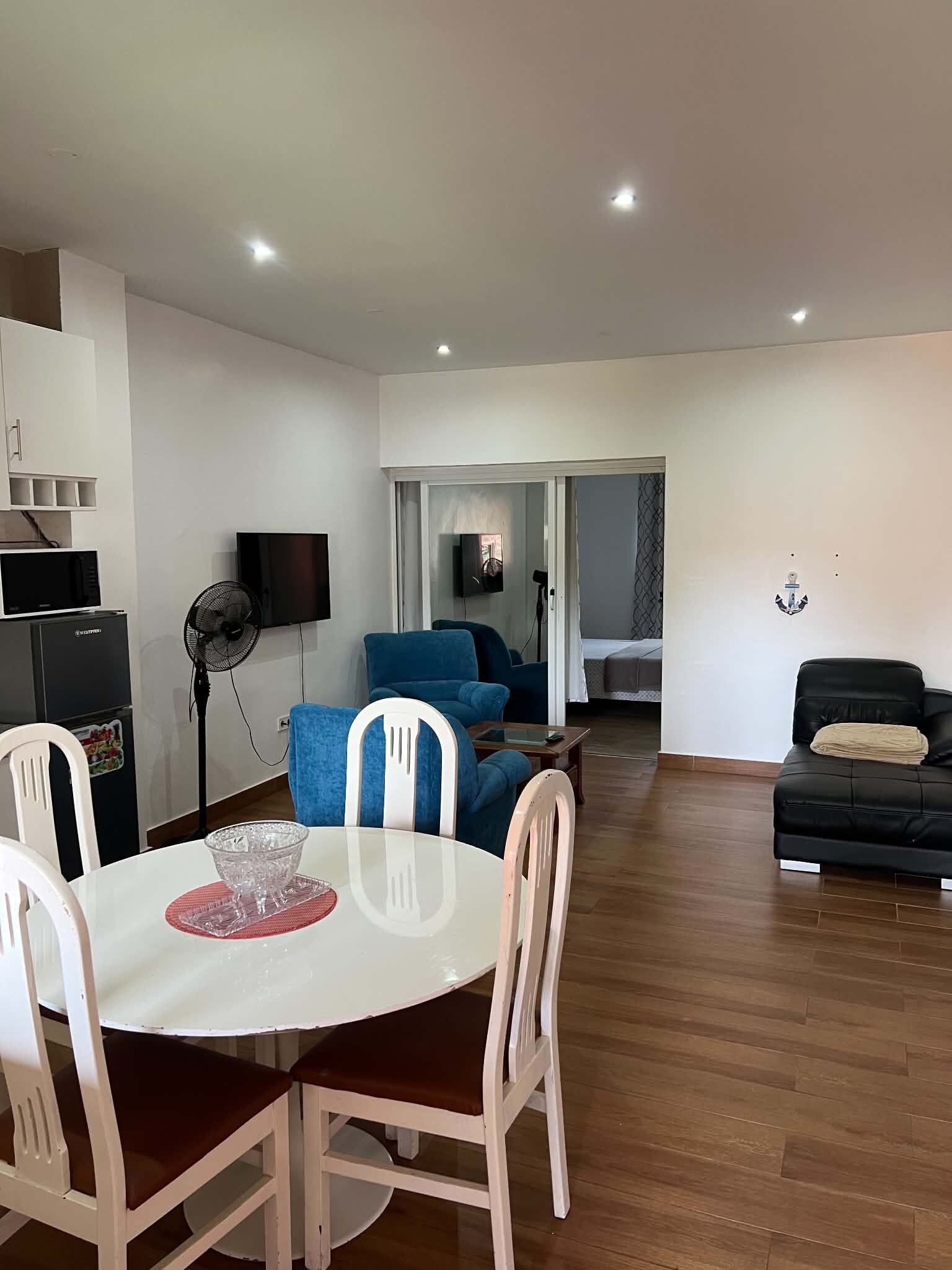 A living room with a dining area, a sofa, a TV, and a ceiling fan.