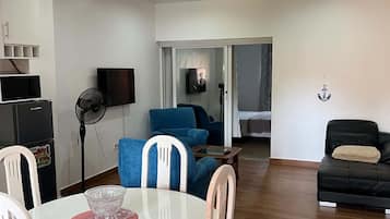 A living room with a dining area, a sofa, a TV, and a ceiling fan.
