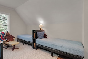 A small, cozy bedroom with two single beds, a nightstand, a lamp, and a chair with a blanket. - Whitetail Ridge Hideaway - Big Canoe, GA (Big Canoe)