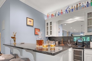 A modern kitchen with a bar area, featuring a wine rack, a framed menu, and a decorative deer figurine. - Whitetail Ridge Hideaway - Big Canoe, GA (Big Canoe)