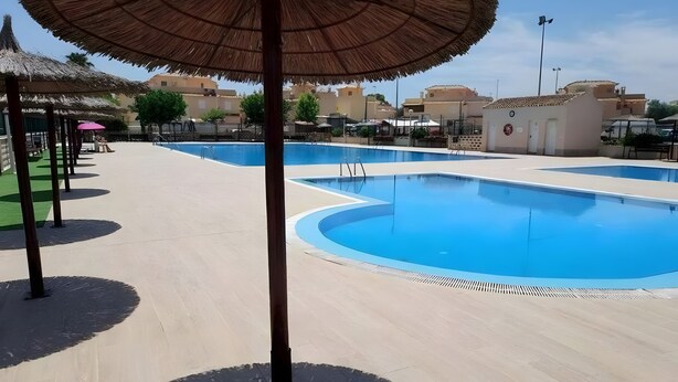 A swimming pool with a clear blue water surface, surrounded by a tiled deck area. - Holiday Home 'Relaxing Cozy House' with Mountain View, Shared Pool and Wi-Fi (Santa Pola)