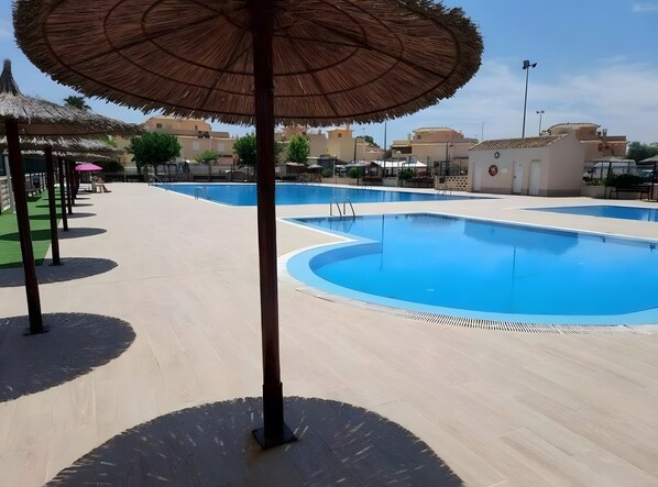 A swimming pool with a clear blue water surface, surrounded by a tiled deck area. - Holiday Home 'Relaxing Cozy House' with Mountain View, Shared Pool and Wi-Fi (Santa Pola)