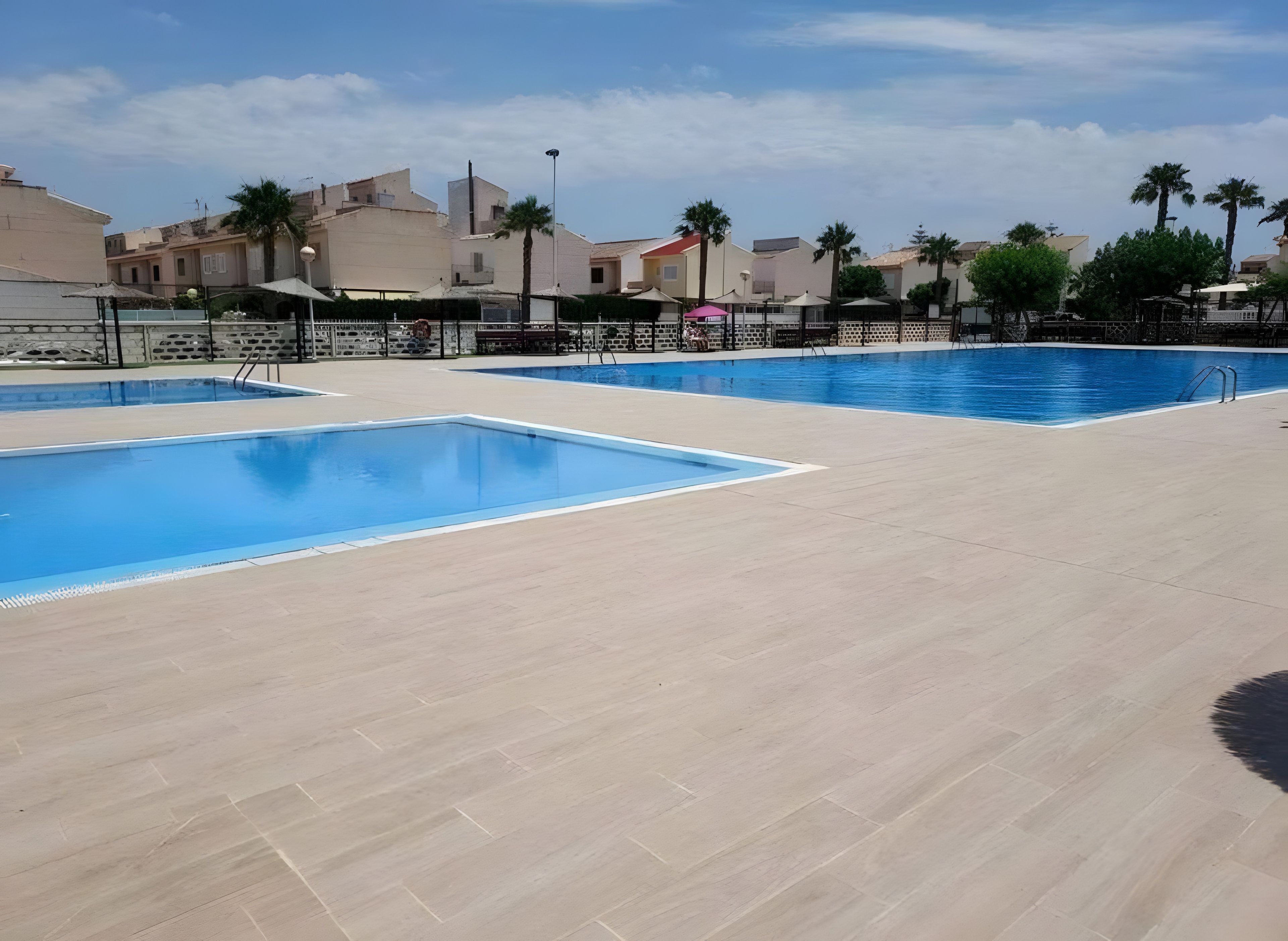 Ein Poolbereich mit mehreren Pools und einer gefliesten Liegefläche.