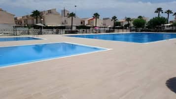Ein Poolbereich mit mehreren Pools und einer gefliesten Liegefläche.
