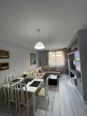 A modern living room with a dining area, a sofa set, a coffee table, and a TV stand. - Modern Cozy Apartment, Close to Pazari i Ri, Tirana Self Check-in Free Wifi (Tirana)