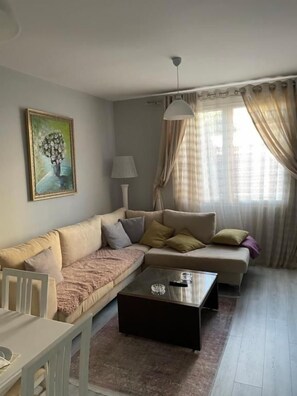 A living room with a sofa, a coffee table, a lamp, and a painting on the wall. - Modern Cozy Apartment, Close to Pazari i Ri, Tirana Self Check-in Free Wifi (Tirana)