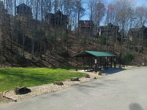 Ein Park mit einem Kiosk, einem gepflasterten Weg und einer Rasenfläche.