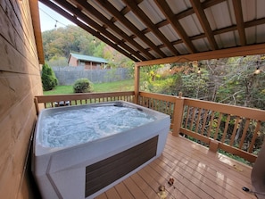 A hot tub on a wooden deck with a view of a house and trees. - Inviting 3BR Cabin - Hot tub & Fireplace - Smokies (Sevierville)