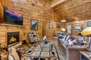 L’intérieur d’une cabane en rondins, avec une cheminée, un canapé en cuir et un coin repas.