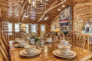 A wooden interior with a dining table set for four, surrounded by chairs. - Serene 4BR Cabin - Hot tub & Game Room - Townsend (Townsend)