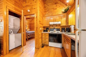 L’intérieur d’une cabane en bois comprend une cuisine, un lave-linge et un lit.