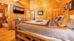 A wooden cabin interior with a bed, a television, and a fireplace. - Serene 1BR Cabin - Hot tub & Fireplace - Smokies (Sevierville)