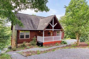 A wooden cabin with a porch, surrounded by trees and a gravel driveway. - Secluded 4BR Cabin - Hot tub & Game Room - Smokies (Sevierville)