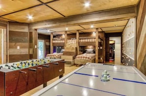 Una stanza con tavolo da calcio, letti a castello e un tavolo da calcio con una striscia blu.