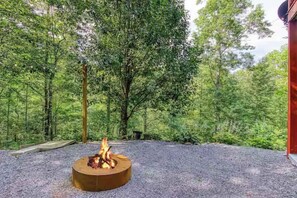 A circular fire pit in a forested area with a gravel ground. - Secluded 4BR Cabin - Hot tub & Game Room - Smokies (Sevierville)
