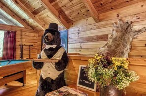 A wooden interior with a pool table, a bear statue, and a mounted animal hide. - Inviting 1BR Cabin - Hot tub & Fireplace - Smokies (Sevierville)