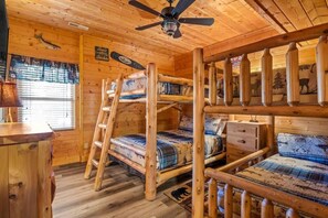 A cabin with bunk beds, a ceiling fan, and a window with blinds. - Bold 7BR Cabin - Home Theater & Hot Tub - Smokies (Sevierville)