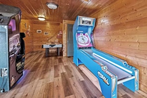 A room with wooden walls and a blue arcade machine labeled 'ICEBALL' and 'ICEBALL PRO'. - Bold 7BR Cabin - Home Theater & Hot Tub - Smokies (Sevierville)