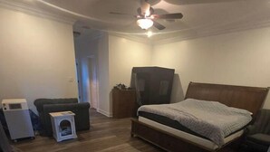 Ein Schlafzimmer mit einem Bett, einem Deckenventilator, einer Heizung und einem kleinen Tisch.
