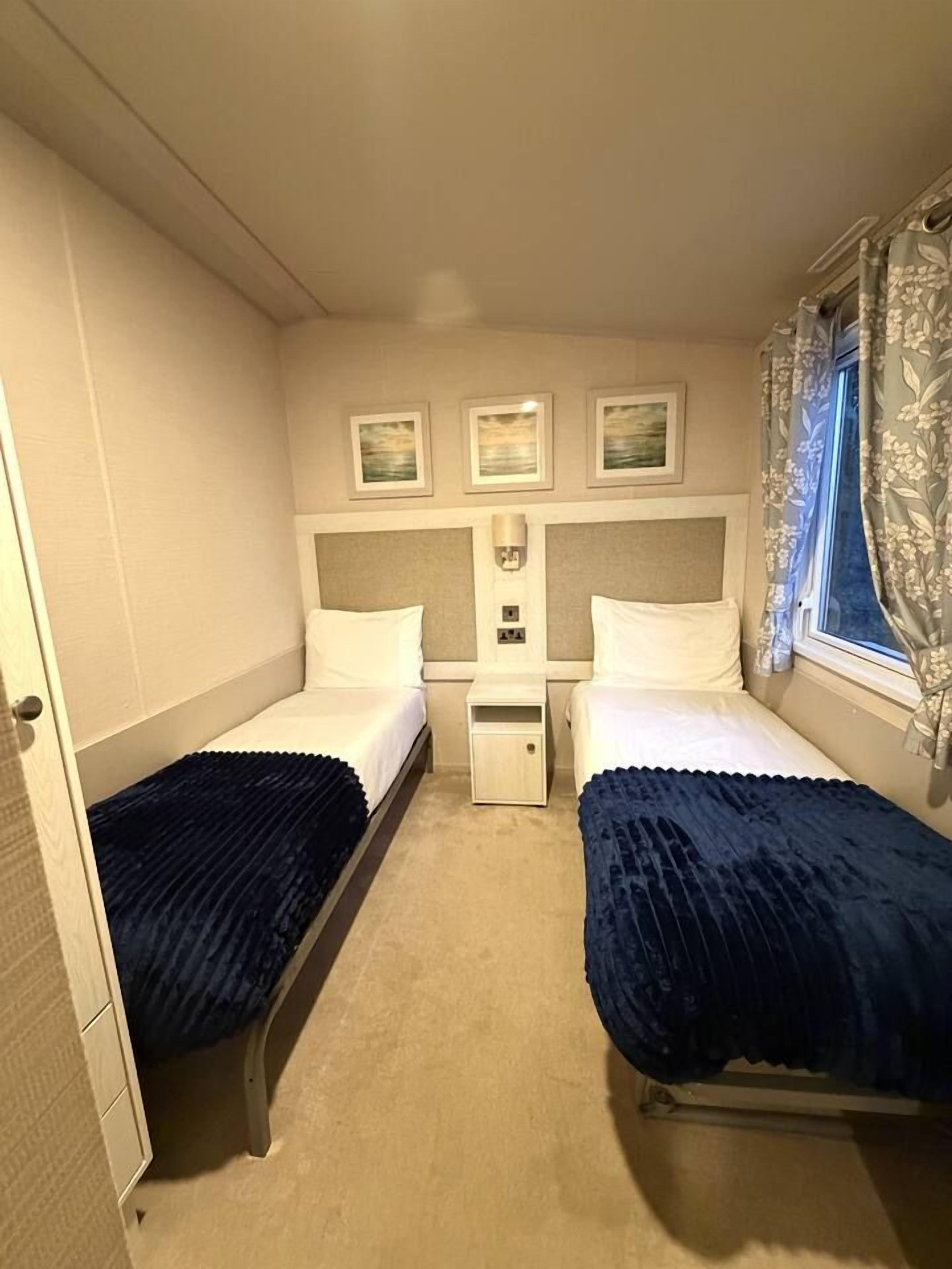 Una habitación de hotel pequeña y con una cama doble, una mesita de noche y una ventana con cortinas.