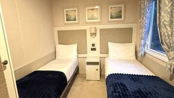 Una habitación de hotel pequeña y con una cama doble, una mesita de noche y una ventana con cortinas.