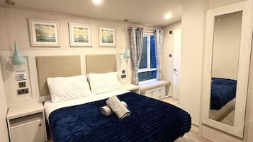 A bedroom with a bed, bedside tables, a mirror, and artwork on the wall.