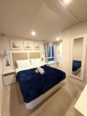 Quarto com cama, mesas de cabeceira, espelho e obras de arte na parede.