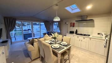 A modern kitchen with white cabinets, a dining area with a table set for four, and a large window overlooking a balcony.