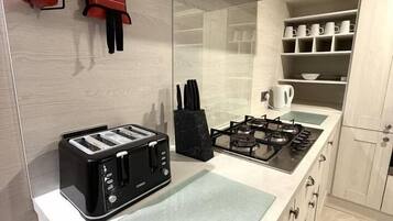 A kitchen with a toaster, a gas stove, a fire blanket, and a fire extinguisher.