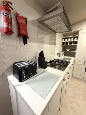 A kitchen with a toaster, a gas stove, a fire blanket, and a fire extinguisher.
