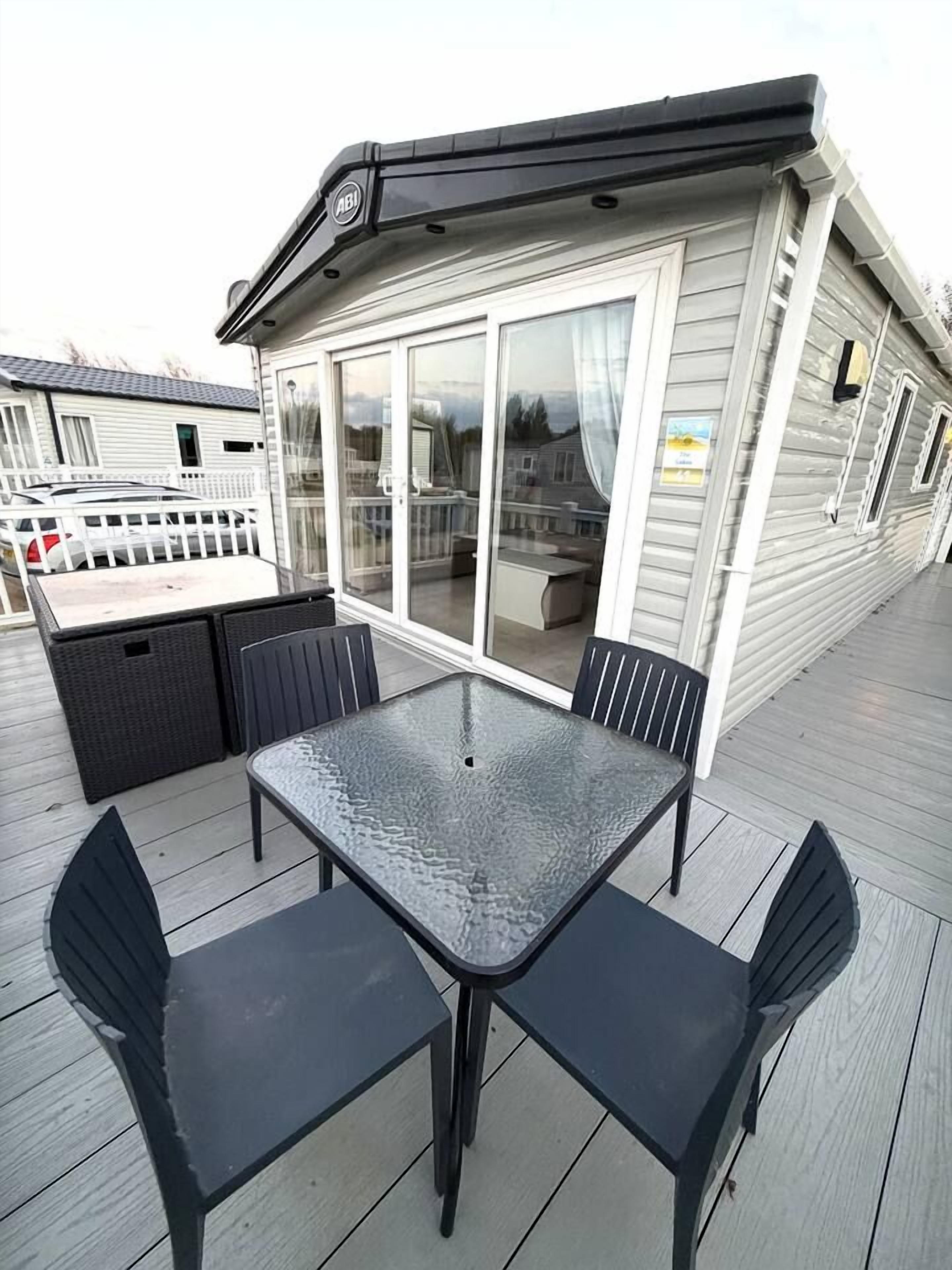 A covered outdoor area with a table and chairs, a sliding glass door, and a white fence.