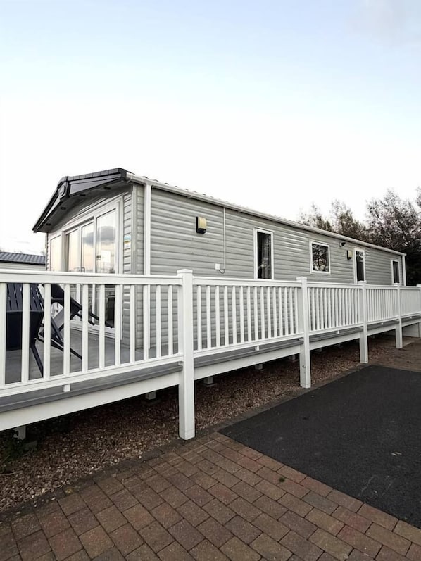 A mobile home with a white deck and a black driveway.