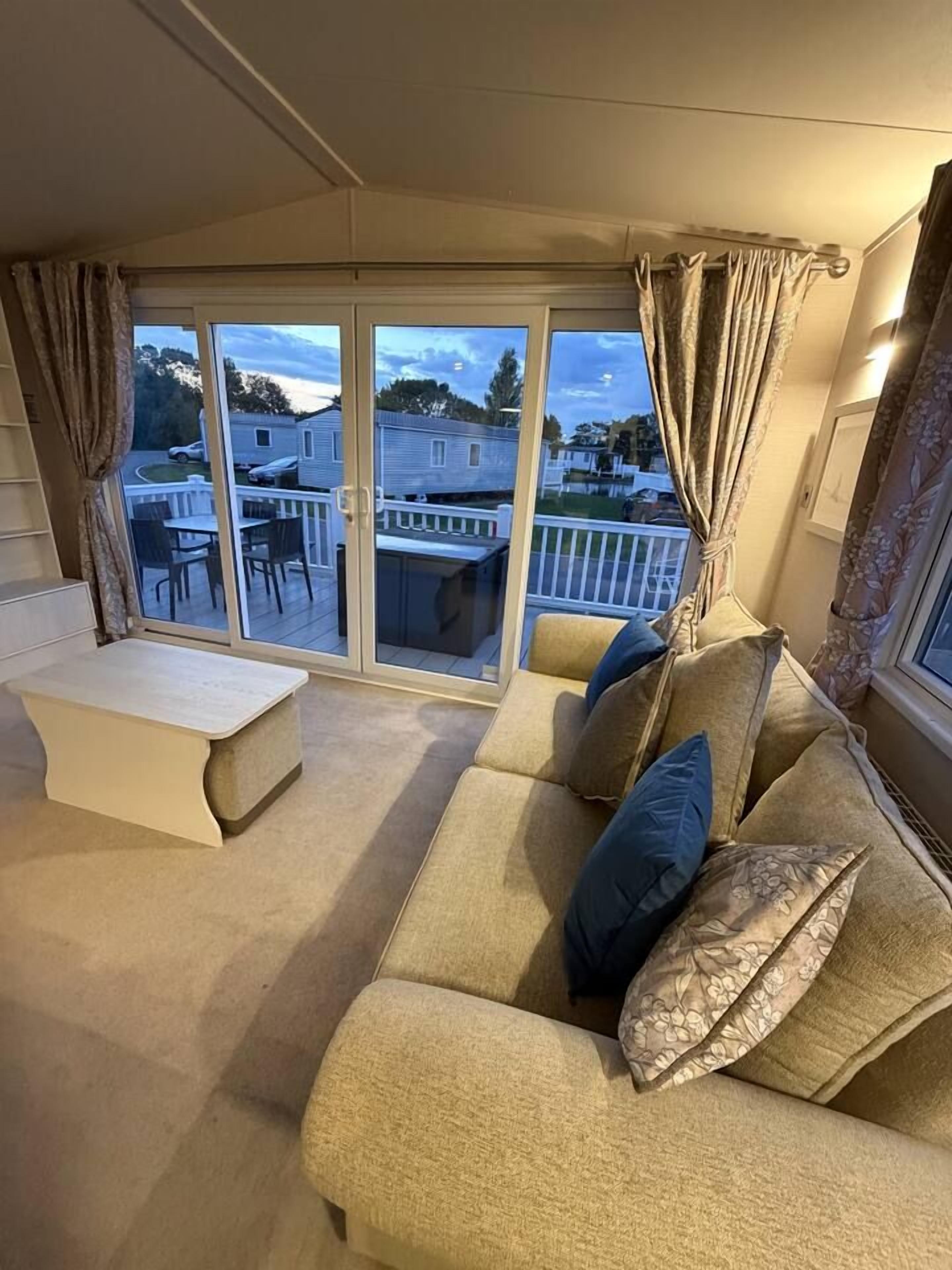 Ein Wohnzimmer mit einer Couch, einer Bank und Blick durch eine Schiebetür auf einen Außenbereich mit Tisch und Stühlen.