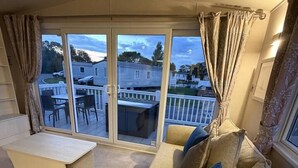 Sala de estar con un sofá, un banco y vistas a un área exterior con una mesa y sillas a través de una puerta corrediza de vidrio.