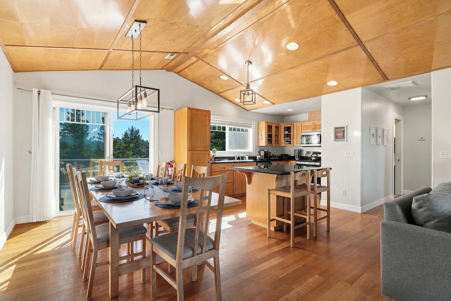 Una cocina amplia con armarios de madera, una isla central y un comedor con una mesa grande y sillas.