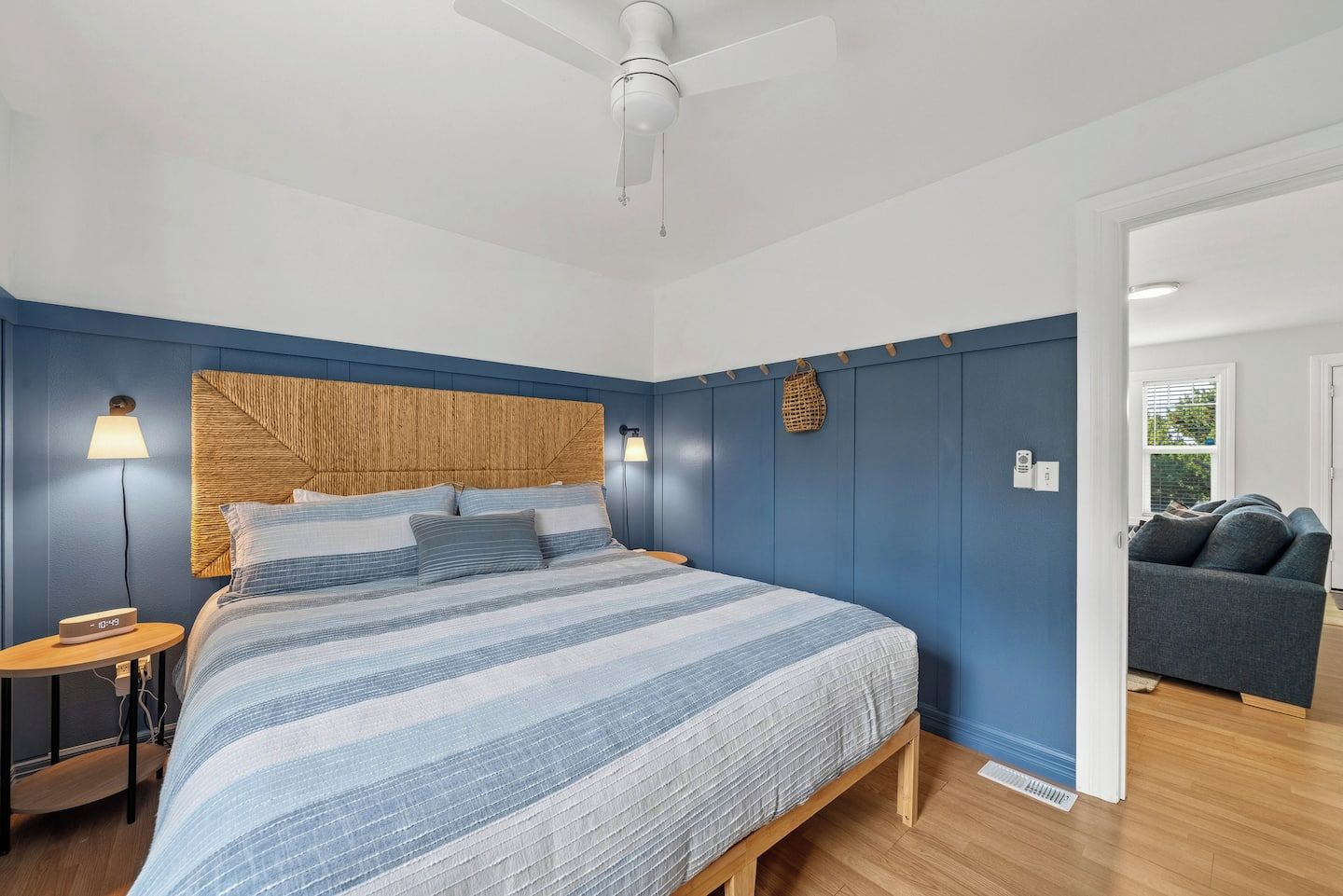 A bedroom with a bed, bedside lamps, a wooden headboard, and a ceiling fan.