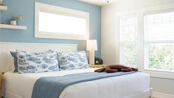 A bedroom with a bed, a ceiling fan, a window with blinds, and a nightstand with a lamp.