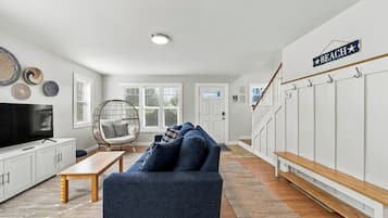 Un salon avec une télévision, un canapé, un fauteuil et un panneau indiquant « PLAGE ».