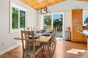 A dining area with a wooden table set for six, surrounded by chairs with cushioned seats. - Sunset Crest | Game Room, Walk to Beach & Town (Manzanita)