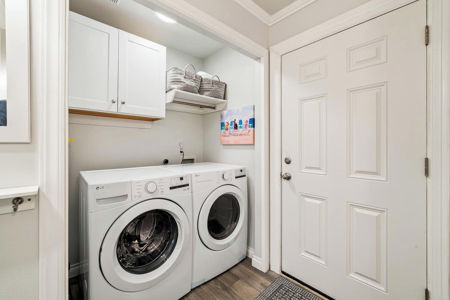 A laundry room with two white LG washing machines, a white door, and a shelf above the machines.