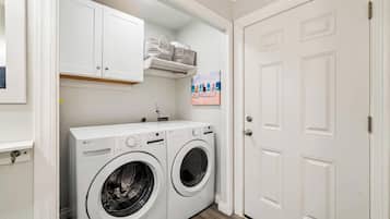 A laundry room with two white LG washing machines, a white door, and a shelf above the machines.